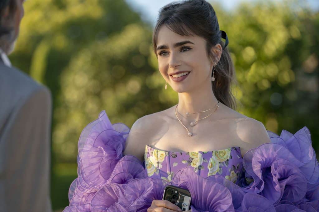 Ashley Park as Mindy Chen speaking to Lily Collins as Emily Cooper in Emily In Paris wearing colourful Nadine Aysoy Jewellery.